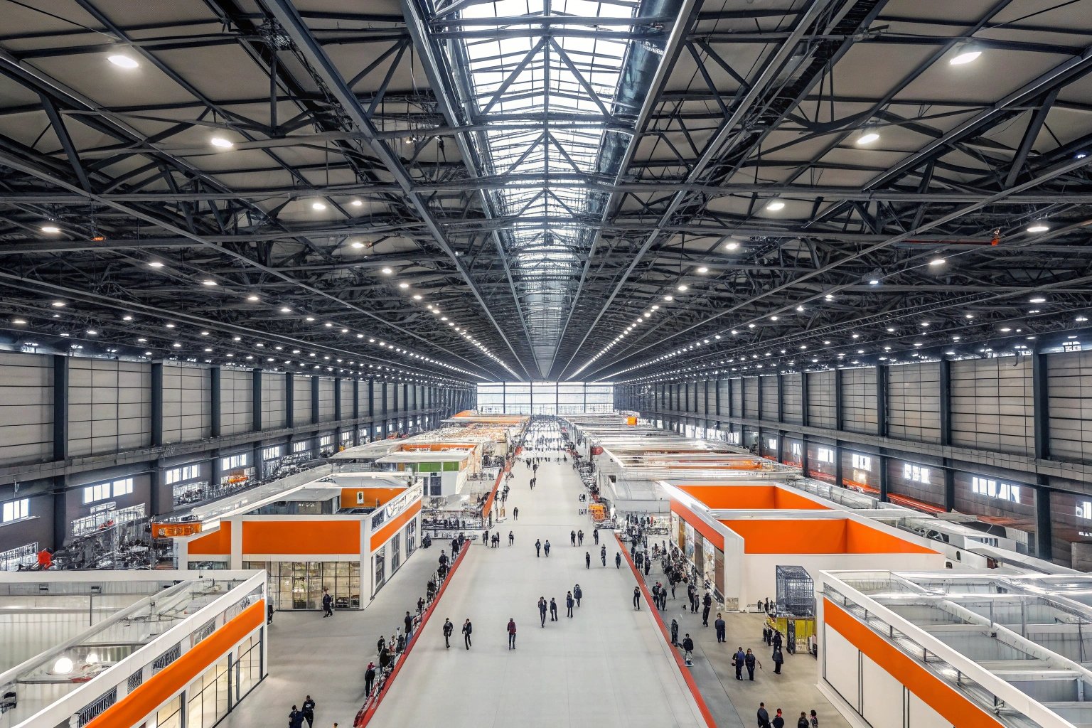 Panoramic industrial exhibition hall with numerous booths and visitors.
